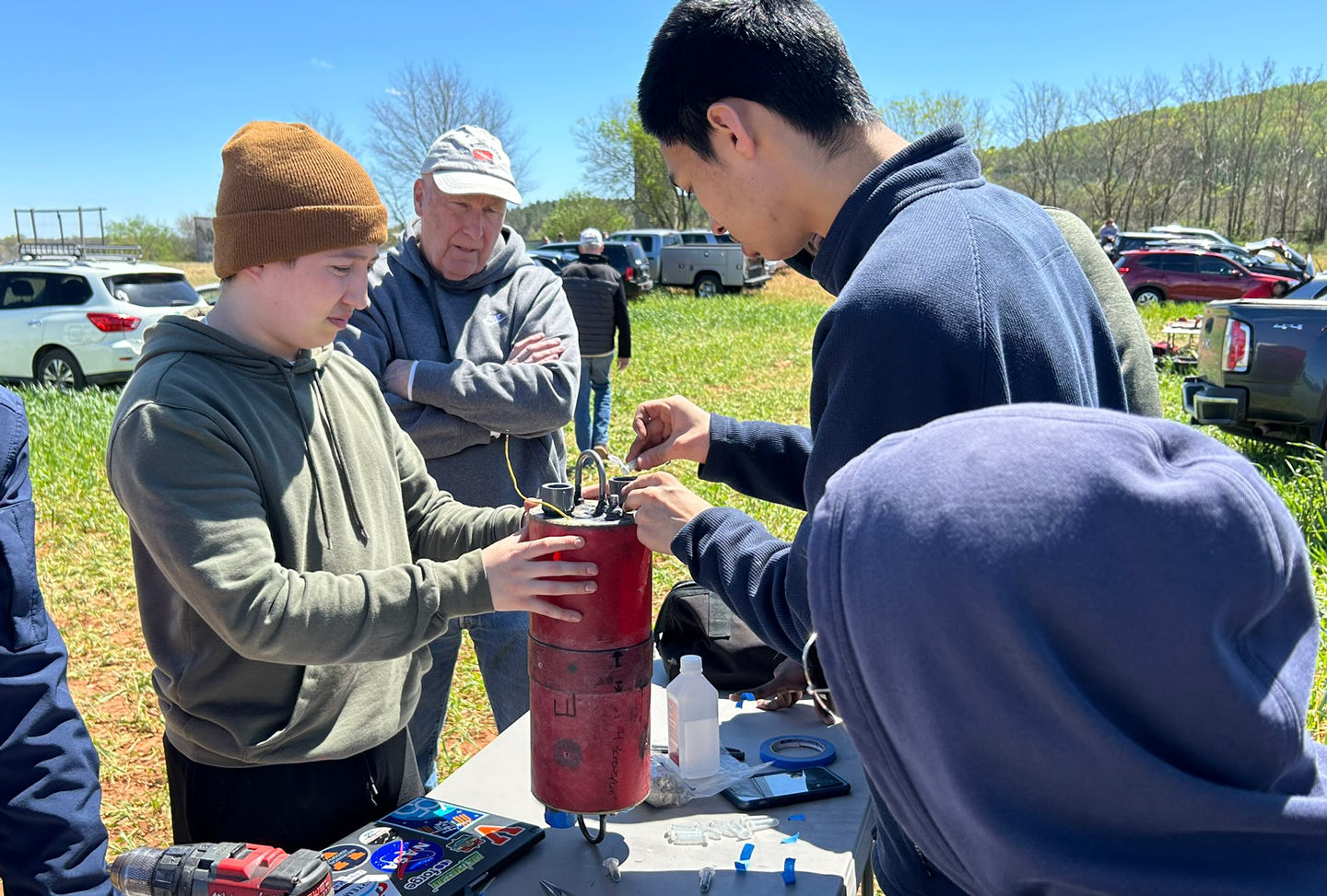 Students working on a rocket part while and advisor observes