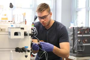 A graduate student works with a piece of equipment in a lab