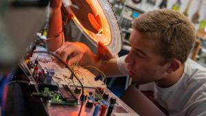 Closeup of male student working on a circuit with an expression of concentration