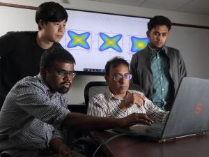 Professor Avik Ghosh with students around a laptop