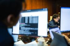 UVA students seated around a conference room table covered with computers, computer monitors, and paper and pencils, work intently during the qualifying round  of the Mid-Atlantic Collegiate Competition.