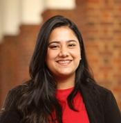 Image of woman in red dress with black blazer smiling