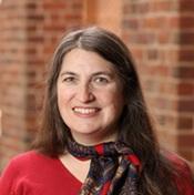 Image of woman in red sweater and patterned scarf smiling outside