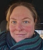 Image of woman smiling wearing a black and green scarf