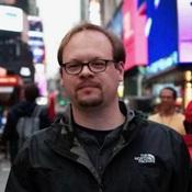 Image of man wearing glasses smiling on a city street
