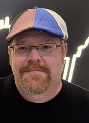 man wearing black shirt and multi-colored beret and glasses smiling