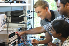Three students working at a lab bench with electronic equipment