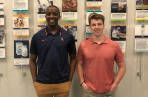 A Black man standing next to a white man in front of a wall decorated with historical photos