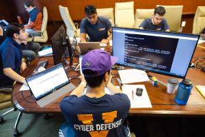 Image of students around table during cyber defense competition