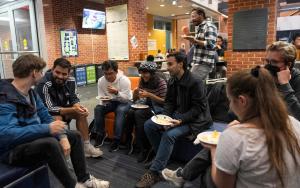 Students of different nationalities sitting in a circle talking, smiling and eating