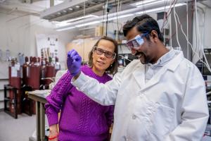 Beth Opila examines a sample in the lab with a student