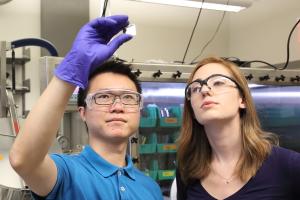 Two students examine a sample that one is holding up to the light