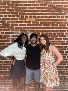 Three students standing in front of a brick wall