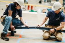 Two students in hardhats make pieces connect.